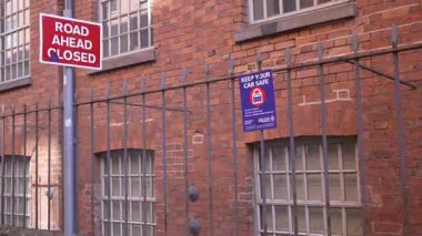 Manchester 'ın Ancoats bölgesindeki bir caddede kırmızı tuğlalı binalar ve kentsel manzaranın yer aldığı 