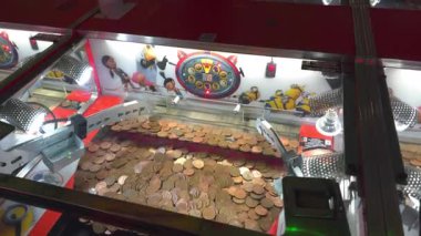 Oyuncuların ödül kazanmak ve itmek için jeton attığı bakır renkli sikkelerle dolu bir oyun makinesi, atari stili para dağıtıcı oyunlarının heyecanını yakalıyor..