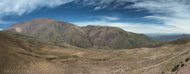 Manzaralı bulutlu mavi gökyüzünün altındaki güzel dağların manzarası.      