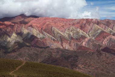 Jeoloji. Humahuaca, Jujuy, Arjantin 'deki renkli Hornocal dağına uzanan kirli bir yol manzarası. Güzel kaya ve gökyüzü dokusu.