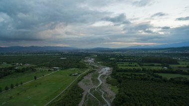 Kırsal alan. Kırsal alanın havadan görünüşü. Nehir tarlalardan, ormanlardan ve dağlardan gün batımında akıyor..