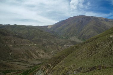 Manzaralı bulutlu mavi gökyüzünün altındaki güzel dağların manzarası.      