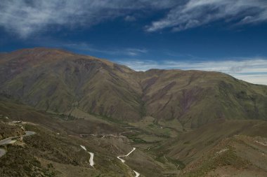 Manzaralı bulutlu mavi gökyüzünün altındaki güzel dağların manzarası.      