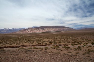 Manzaralı bulutlu mavi gökyüzünün altındaki güzel dağların manzarası.      