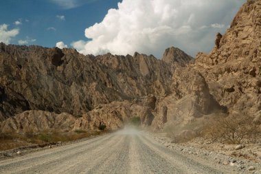 Macera. Kurak çöl. Tozlu toprak yol boyunca kayalık vadi ve kumtaşı tepeleri boyunca sürüyorum.. 