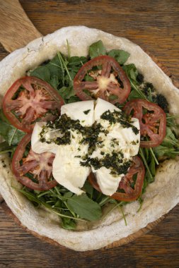 İtalyan pizzası. Burrata peynirli, soslu, domatesli ve roka aromalı pizzanın yakın görüntüsü..