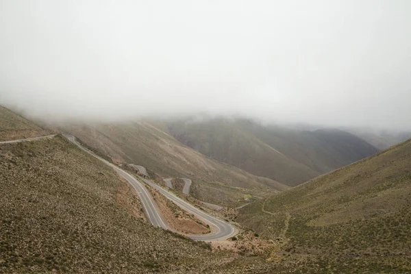 道路は山の中で高い 雲に覆われた空の下のアンデス山脈を横切り リパン坂と呼ばれる滑らかなアスファルトの高速道路の眺め — ストック写真