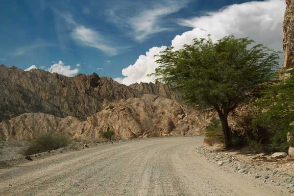 stock image Travel. Driving along the dusty dirt road in the arid mountains. The sandstone hills and rocky formations under a beautiful sky. 