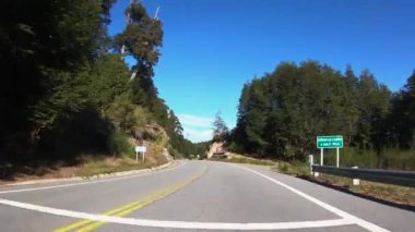 Bulutlu bir günde asfalt otoyol boyunca dağları ve ormanı geçen bir arabanın bakış açısı. 