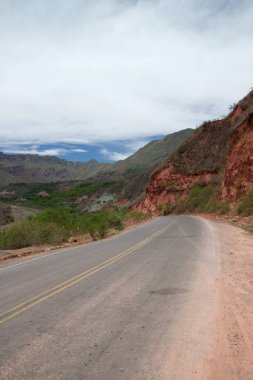 Yeşil tepeler ve kumtaşı oluşumları boyunca kırsal yol. Dağların yükseklerinde, boş asfalt yolda seyahat ediyor..