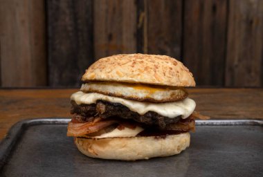 Ekmek, ızgara yumurta, et, provolone peyniri, kıtır pastırmalı bir hamburgerin yakın görüntüsü.