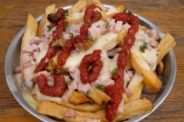 Jambonlu kızarmış patates, mozzarella peyniri, ketçap, soğan ve ahşap kaplama metal bir çanakta taze keklik otu.. 