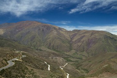 Keşfedin. Popüler Piskopos yamacının karşısındaki kırsal yol manzarası. Çayırlar, vadiler ve tepeler dramatik bulutlu gökyüzünün altında.
