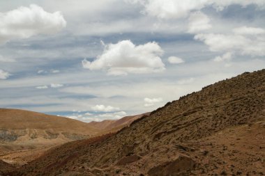 Andes sıradağları. Güzel bulutlu bir gökyüzünün altındaki kahverengi dağ zirvesinin havadan görünüşü. 