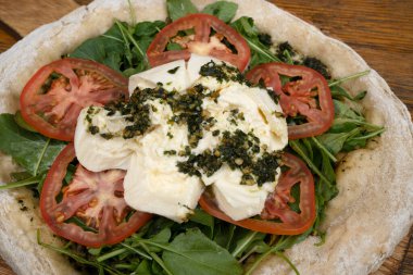 İtalyan pizzası. Burrata peynirli, soslu, domatesli ve roka aromalı pizzanın yakın görüntüsü.. 