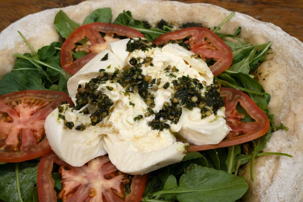 İtalyan pizzası. Burrata peynirli, soslu, domatesli ve roka aromalı pizzanın yakın görüntüsü.. 