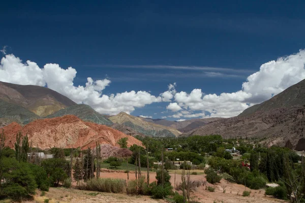 stock image Idyllic landscape. Panorama view of the Seven Color Hill and village in Purmamarca, Jujuy, Argentina. The green valley and colorful mountains under a blue sky. 