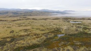 Sonbahar renkleri. Kırsal alan. Sarı çayır, tepeler, nehir ve vadi, sisli bir sabah manzarası..
