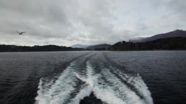 Yolculuk. Günbatımında Nahuel Huapi Gölü 'nden geçen yatın bıraktığı su izinin görüntüsü.. 