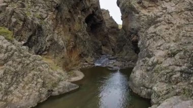 Seyahat et ve keşfet. Uçurumlardaki bir nehri takip eden hava görüntüsü. Kayalık kanyon boyunca akan suyun görüntüsü. Kaya duvarı ve uçurum farklı dokular yaratır..