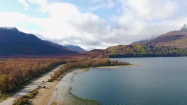 Patagonya 'daki Falkner Gölü' nün havadan görünüşü Arjantin. Sonbaharda Kızıl Orman 'ın karşısındaki yol manzarası ve göl kıyısının yanı sıra. Arka plandaki And Dağları.