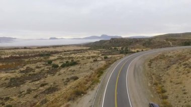 Kırsal yol. Sonbaharda sarı çayır ve tepeler boyunca asfalt yolun havadan görünüşü..