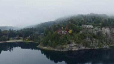 Moreno Gölü 'nün ve ormanın sisli bir sabahında havadan görünüşü. Kıyı şeridi manzarası, kayalık kayalıklar ve Bariloche, Patagonya Arjantin ormanlarındaki evler.