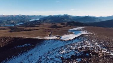 Villa Pehuenia, Patagonya Arjantin 'deki Bate Mahuida volkanı üzerinde uçan hava manzarası. Kahverengi arazi, dik uçurum ve ufuktaki And Dağları 'nın gün batımında görüntüsü..