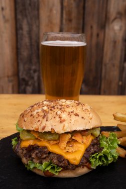 Dev hamburger. Peynirli, marullu, domatesli, soğanlı, ızgara etli, kızarmış pastırmalı ve patatesli nefis bir hamburgerin yakından görüntüsü..