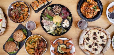 Restoran masasında yemek var. Ahşap arka planda farklı tabakların yakın görüntüsü. Dilimlenmiş salam, peynir, mavi peynir, Focaccia ekmeği, İtalyan boconccinosu, ceviz, jambon, pişirilmiş jambon ve ahşap masada yeşil zeytin..              