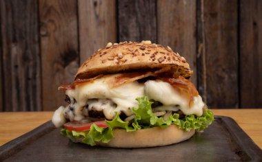 Dev hamburger. Peynirli, marullu, domatesli, soğanlı, ızgara etli, kızarmış pastırmalı ve patatesli nefis bir hamburgerin yakından görüntüsü..