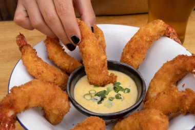 Deniz ürünleri. Ahşap masadaki beyaz kasede soslu kızarmış karideslerin yakın plan görüntüsü..