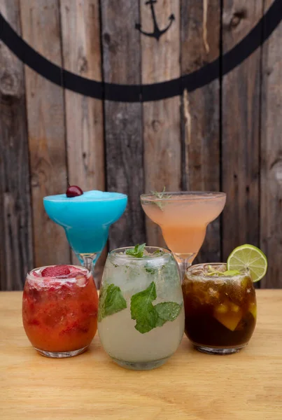 快乐时光三只玻璃杯和两杯带有木制背景的含酒精热带饮料的合影 — 图库照片