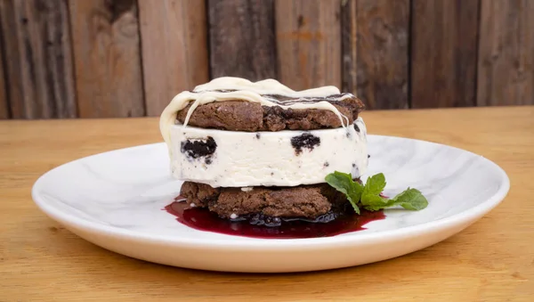 甘いデザートだ 木製の背景を持つ白い皿に果実を含むアイスクリームクッキーケーキのクローズアップビュー — ストック写真