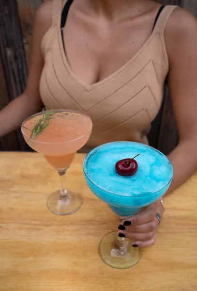 夜のカクテル 2つのアイステキーラベースの飲み物を持つ若い女性のクローズアップビュー 青い柑橘系のマルガリータとピンクのグレープフルーツマルガリータ — ストック写真
