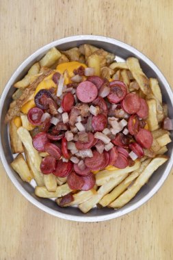 Kızartma. Dilimlenmiş sosis ve kıtır pastırmalı kızarmış patatesler ahşap arka planda metal bir kapta..