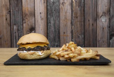 Çedarlı ve soğanlı geleneksel bir çizburger tutan kadın..