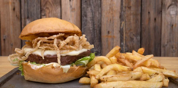 Bitki bazlı burger. Burger değil. NotCo hamburgerin yakın plan görüntüsü, marul, çıtır soğan halkaları, peynir, Notco mayonez ve patates kızartması, ahşap arka planda metal bir çanak içinde..