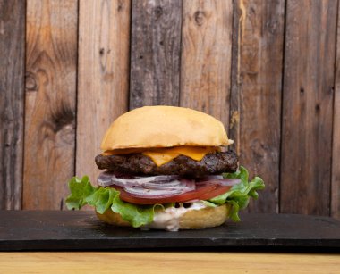 Amerikan yemeği. Marul, domates, çedar peyniri, kırmızı soğan ve mayonezli hamburgerin yakından görüntüsü..