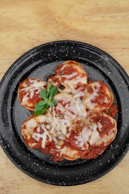 Doldurulmuş makarna. Akdeniz domates sosu ve ahşap masadaki siyah tabakta Provolone peyniri ile Sorrentinos 'un en üst görüntüsü..