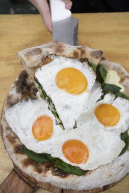 Pizza yiyorum. Bir kadının mozzarella peyniri, ıspanak ve kızarmış yumurtayla servis ettiği yakın çekim görüntüsü..