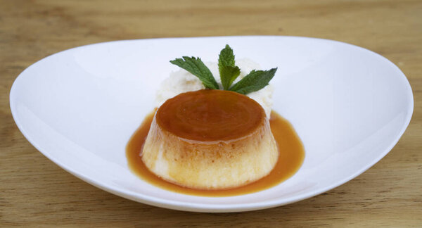 Традиционный десерт для гурманов. Крупный план пирога со сливками и карамелью, в белом блюде на деревянном столе. 