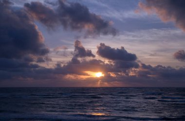 Cennet. Deniz ve okyanus gün doğumunda dalgalanır. Şafak turuncu ve mor renkler.