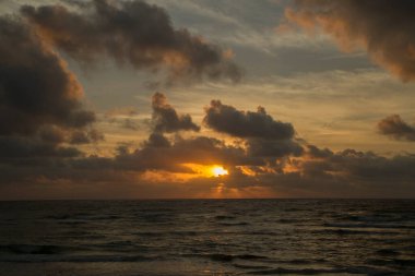 Cennet. Deniz Burnu. Deniz ve okyanus gün doğumunda dalgalanır. Güzel şafak turuncu, sarı ve kırmızı renkler suda, gökyüzünde ve bulutlarda. 