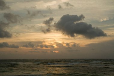 Aman Tanrım! Dramatik sahil manzarası. Turuncu güneş ışınları ve bulutlarla güzel gün batımı gökyüzü, deniz üzerinde ve alacakaranlıkta okyanus dalgaları. 