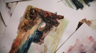 Atölyede sanat eserleri. Hareket atışı. Resim stüdyosunun zeminindeki bir tablonun en üst görüntüsü. Kamera, okyanusun doğal bir manzarasını gösteren anlamlı bir resmin üzerinde döner..