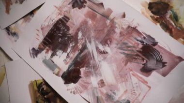 Sanat eserleri. Hareket atışı. Sanat stüdyosunun zemininde duran çağdaş bir tablonun üst görüntüsü. Güzel fırça darbesi dokusu, desen ve pembe ton paleti.