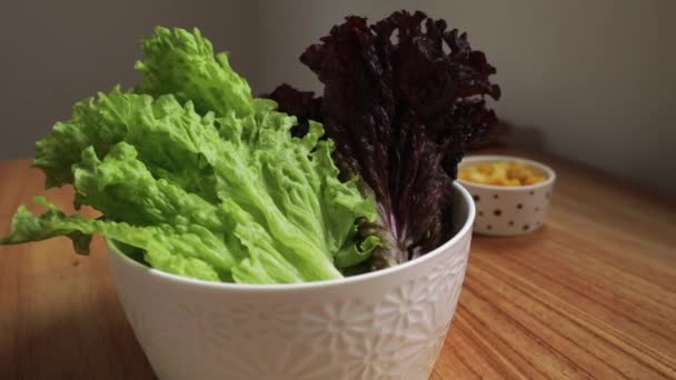 健康的配料可用于烹调 在厨房木制桌子上的碗里放着新鲜的红绿相间的生菜 — 图库视频影像