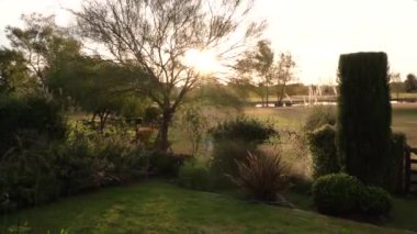 Bahçıvanlık. Fıskiye hortumla bağlanmış, gün batımında bahçeyi sulıyor..