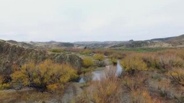 Vadiden ve dağlardan akan nehrin havadan görünüşü. Toprak yol manzarası, sarı çayır, tepeler ve Patagonya 'daki kayalık uçurum..